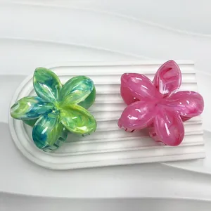 Dettaglio di fermacelli per capelli plumeria marmorizzati verde e rosa su vassoio