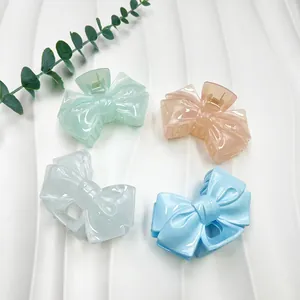 Set of four pastel bow-shaped hair claws in mint, pink, white, and blue resin