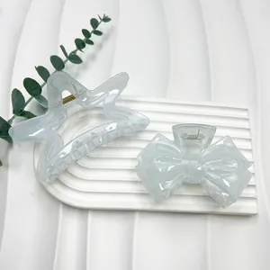Detailed view of light blue star and bow hair clips with marble texture and gold springs