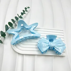 Detail of light blue star and bow hair claw clips on white textured display stand