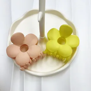 Dettaglio di mollette per capelli a fiore opache color pesca e giallo su vassoio bianco