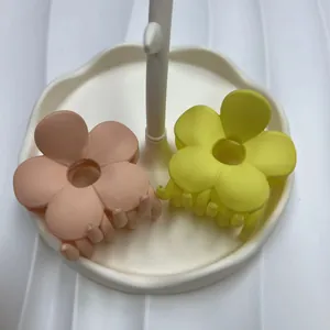 Dettaglio mollette per capelli a fiori opachi in rosa e giallo con finitura gommata