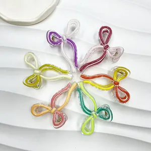 Set of 6 colorful acrylic bow hair claws with gold springs on white ripple background
