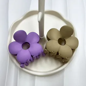 Dettaglio macro di mollette per capelli a fiore opaco in viola e verde oliva