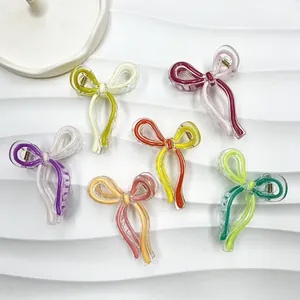 Bow-shaped jelly acrylic hair claws in six color variants on a white textured tray