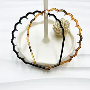 Detail van golvende haardbanden met tanden in zwart en amber op een witte houder