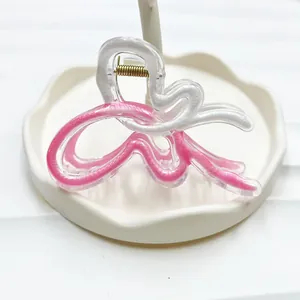 Detail of a wavy acrylic shark hair claw with pink and white patterns in a ceramic tray