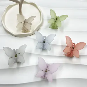 Détail de six pinces à cheveux papillon mates aux couleurs pastel sur texture ondulée