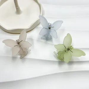 Détail de pinces à cheveux papillon en rose bleu et vert mat avec ressort métallique