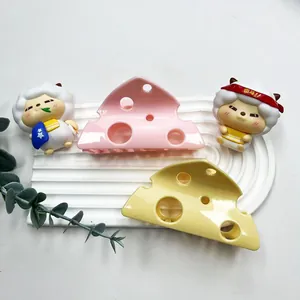 Set of two cute cheese-shaped hair claws in pink and yellow on a white display stand