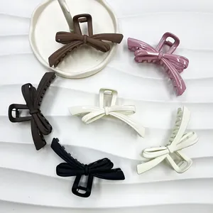 Elegant large bow hair claws in various colors like matte black and cream on white background