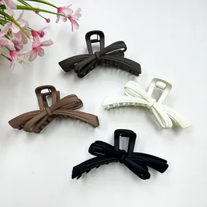 Detail view of large bow hair claws in matte brown, coffee, cream, and black colors