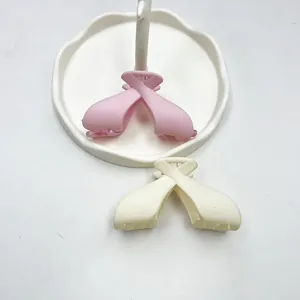 Close-up of matte pink and cream bow hair claws on a white decorative ceramic tray