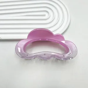 Close-up of translucent pink pearl cloud claw clip on a minimalist white tray