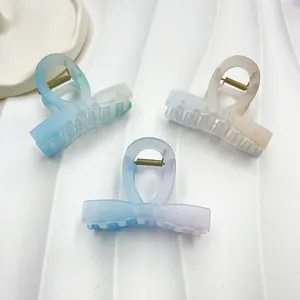 Three gradient frosted hair claws in blue-green, beige, and purple on a white tray