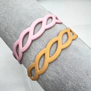Detail of matte pink and yellow hollow leaf woven headbands on a grey display