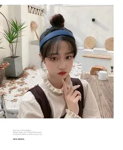 Dettaglio di un cerchietto largo blu scuro opaco indossato da una modella all'aperto