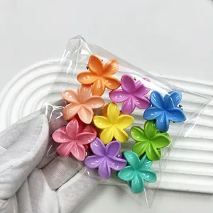 Close-up of colorful mini flower hair claws held in hand on a white background