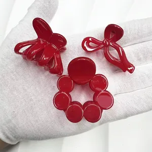 Détails de trois mini pinces à cheveux rouges de formes variées sur une main gantée
