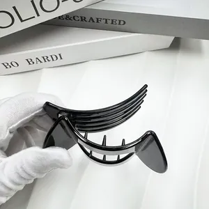 Detail view of large glossy black hair clip held in hand showing smooth resin finish
