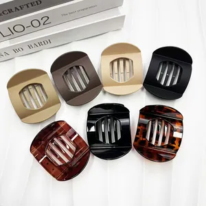 Set of 7 matte and glossy large claw hair clips in neutral colors on white background