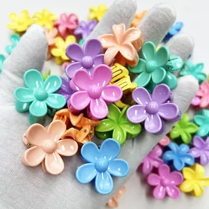 Macro shot of colorful mini flower hair clips held in hand with glossy resin finish