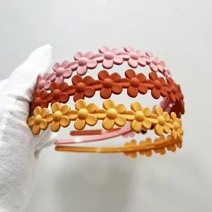 Set di tre cerchietti opachi con margherite in colori pastello rosa, arancione e giallo