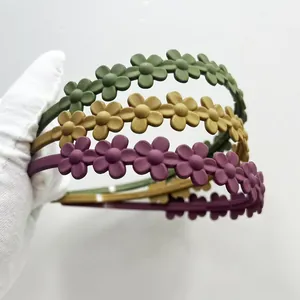Dettaglio di cerchietti a fiori opachi in verde scuro, giallo e viola con texture opaca