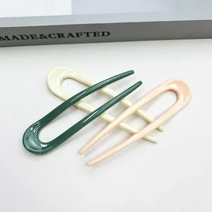 Three minimalist U-shaped hairpins in dark green, cream, and pink glossy resin finish