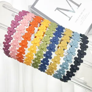 Cerchietti per capelli opachi a fiori in colori pastello disposti su un supporto