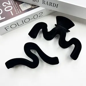 Detail of large black flocked hair claw clip with velvet wave design on a book