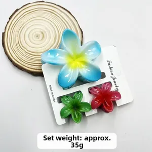 Three-piece plumeria flower hair clips set in blue, green, and pink on display card