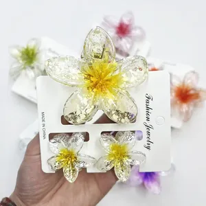 Handheld yellow plumeria flower hair claw clip set with gold foil and translucent resin