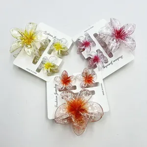 Detail of floral plumeria hair clip set with glitter resin finish and shark claw grip