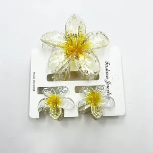 Close-up of three-piece plumeria hair clip set with sparkling glitter finish on white card