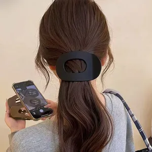 Détail d'une pince à cheveux ovale noir mat fixant une queue de cheval avec style