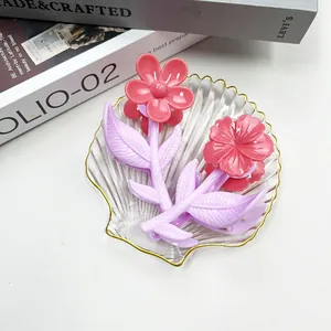 Dettaglio di fermagli per capelli a forma di fiore rosa e viola su vassoio di vetro