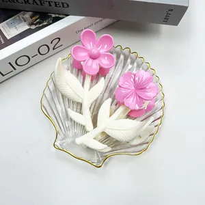 Dettaglio di fermacapelli a fiori rosa con petali in un vassoio decorativo a conchiglia