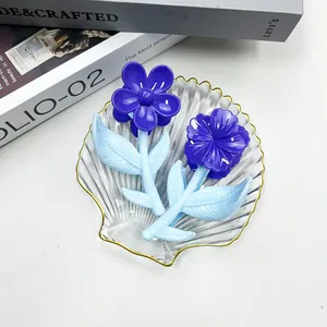 Dettaglio di fermagli per capelli a fiore blu su vassoio in vetro con finitura in resina