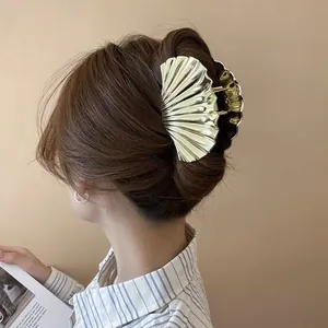 Primer plano de pinza dorada para el cabello en forma de abanico con textura de concha