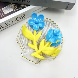 Dettaglio di fermagli per capelli a forma di fiore blu con base gialla su vassoio