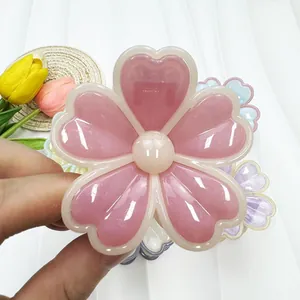 Détail macro de la pince à cheveux fleur rose avec pétales en cœur et résine brillante