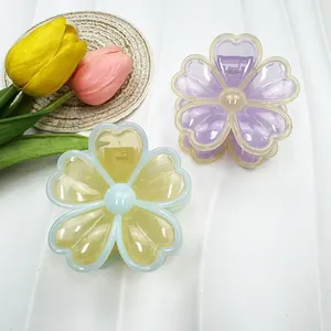 Détail de pinces à cheveux en forme de fleur translucide mauve et jaune sur fond blanc