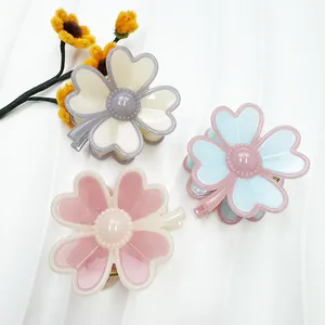 Detailed macro view of three resin flower hair claws in cream, blue and pink pastel colors