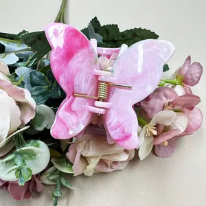 Detailed view of pink marble butterfly hair claw with golden metal spring mechanism
