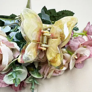 Detail view of double-layered marble pattern butterfly hair claw with gold metal spring