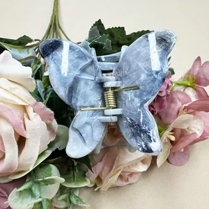 Detail of a marble-textured butterfly hair claw clip with a golden spring mechanism