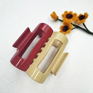 Detail of large burgundy and beige rectangular hair claws with glossy finish and metal spring