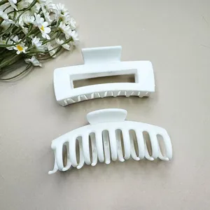 Detail view of two white soft silicone hair claws in rectangular and curved designs