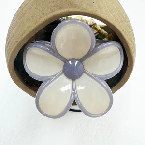 Close-up of a jelly-textured frangipani hair claw clip with creamy white flower petals